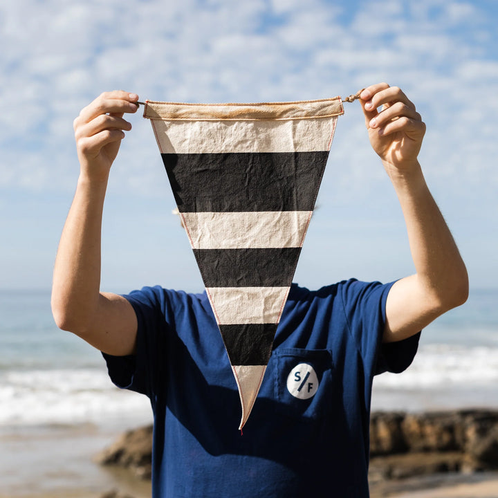 Person holding a striped fabric against a beach background