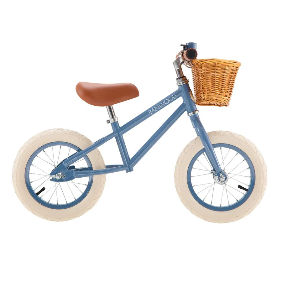 Blue children's balance bike with a wicker basket on a white background