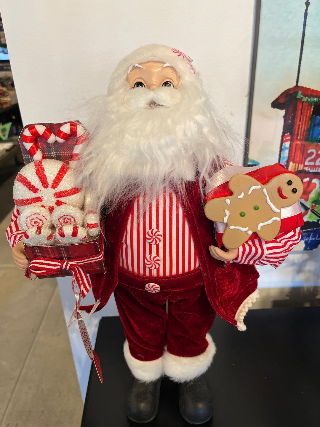 Decorative figure of a Santa Claus with gingerbread man and candy cane elements on a white surface.