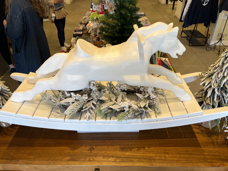 Decorative display with white horse sculptures on a wooden base in a store setting.