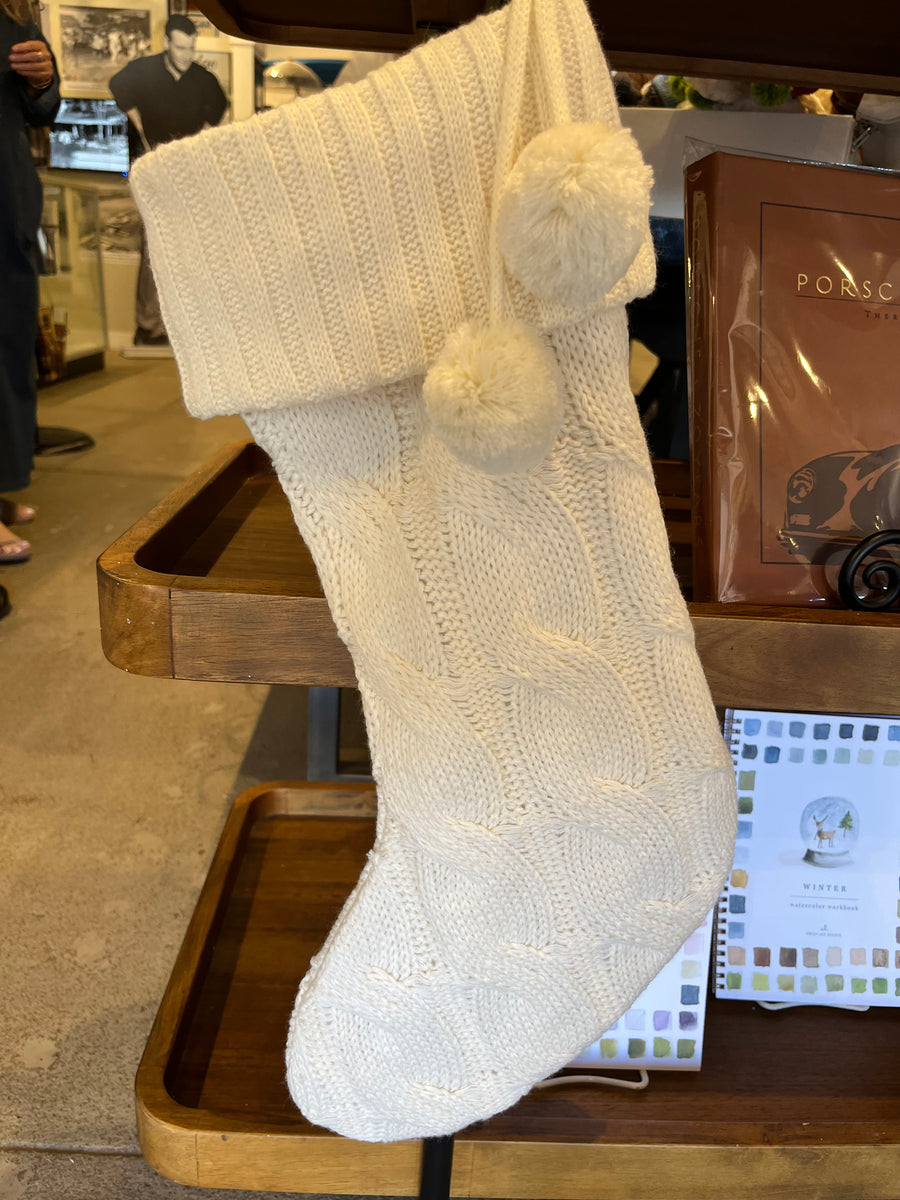 Knitted blanket with pom-poms on a wooden surface