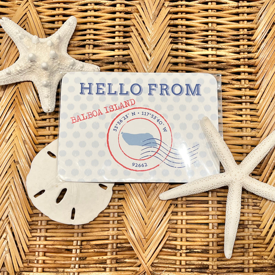 Card with 'Hello from Balboa Island' text on a woven surface with starfish and sand dollar.