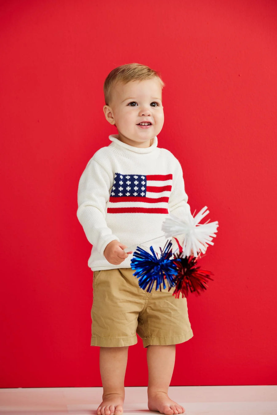 Child wearing a sweater with an American flag design against a red background