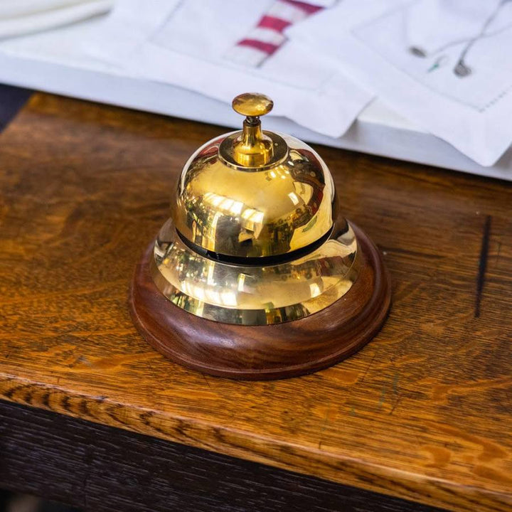 Gold service bell on a wooden surface with papers in the background